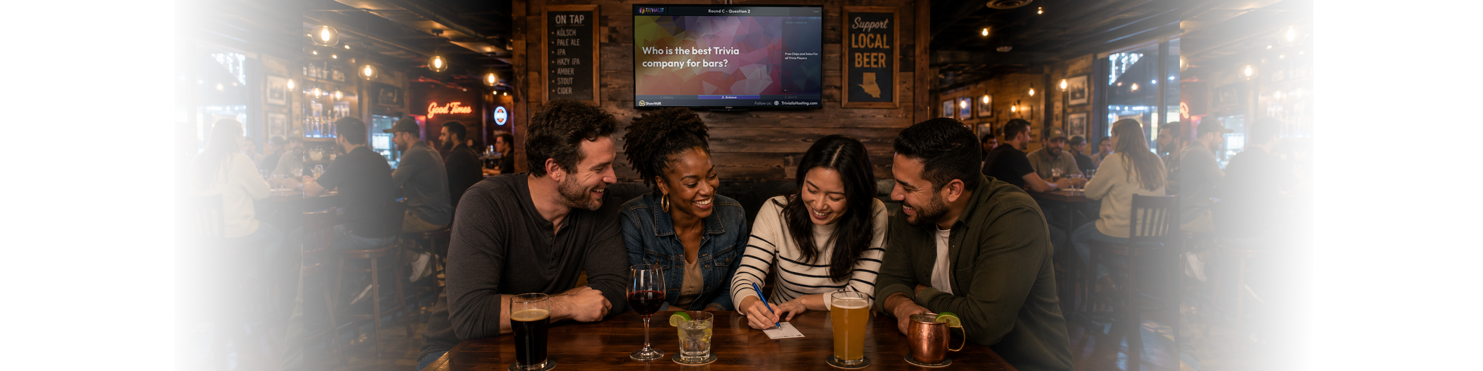 Four friends laughing together at a bar table, writing answers on a trivia sheet during a Trivialis Hosting show